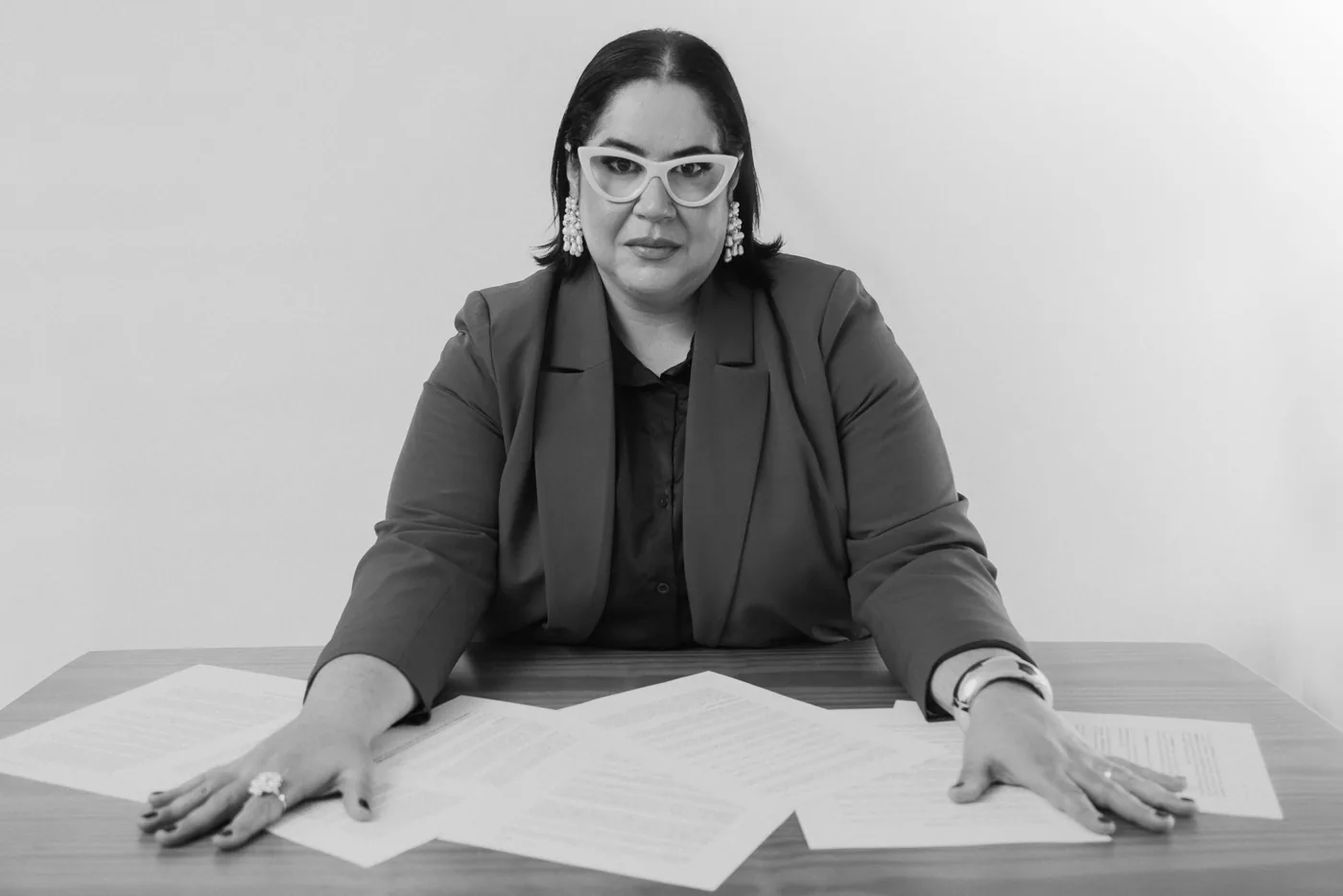 Viviane Veiga Távora à mesa, com as mãos sobre folhas organizadas